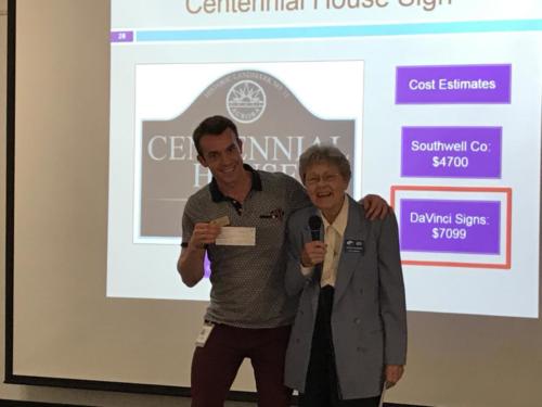 Aurora's Historic Preservation Specialist D. Brownfield receives a check for Centennial House Signage.